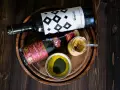 Zutaten für ein köstliches Balsamico-Dressing: eine Flasche Olivenöl, eine Flasche Aceto Balsamico Giuseppe Giusti und eine Schale mit grünen Kräutern.