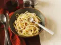 Eine Schüssel Spaghetti mit Speck und Pfeffer, eine köstliche Carbonara ohne Ei, serviert mit einem Glas Rotwein.