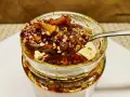 Ein Löffel voller knusprigem Chiliöl mit Sesam und Gewürzen, bereit, Gerichte zu verfeinern.