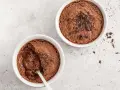 Zwei Schokoladenmousse-Portionen, garniert mit Schokostückchen. Ein Löffel steckt in einer der Schalen, bereit für ein schnelles Dessert.