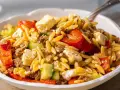Herzhafter Kritharaki Salat mit Hackfleisch, Feta, Gurke und roten Paprikastücken. Ein köstliches Gericht, das alle Geschmacksnerven verwöhnt.