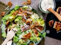 Frischer Caesar Salat mit gegrilltem Hähnchen, Croutons und Parmesan. Dazu ein Glas mit cremigem Caesar Salat Dressing.