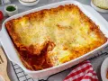 Herzhafte Lasagne mit Schmand und goldbraun überbackenem Käse in einer weißen Auflaufform.