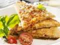 Herzhafte Hauptspeise: knusprige Eierkuchen-Schnitten mit Tomaten und Parmesan, garniert mit Basilikum und Kirschtomaten.