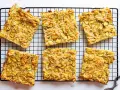 Sechs rechteckige Stücke Zucchini Scarpaccia liegen auf einem schwarzen Gitterrost.