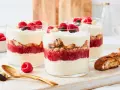 Schichtdessert mit Himbeeren, knusprigen Keksen und cremigem **dessert mit mascarpone**, garniert mit frischen Beeren und Schokolade.