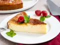 Ein Stück cremiger Kuchen mit griechischem Joghurt, garniert mit Himbeeren und Minze.