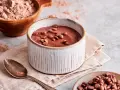 Schokoladenpudding, frisch zubereitet, mit Schokostückchen garniert. Perfekt, um Pudding selber machen zu lernen.
