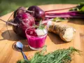 Rote Bete Mus Rezept: Frische rote Bete, Meerrettich und Dill auf Holztisch. Ein Glas mit leuchtend pinkem Mus, garniert mit Würfeln und Dill.