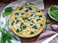 Herzhafte Spinat Lachs Quiche mit frischem Dill garniert, bereit zum Servieren.