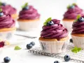 Mehrere Muffins mit lila Beeren-Topping, garniert mit frischen Blaubeeren und Minze. Ein einfacher, köstlicher Genuss.