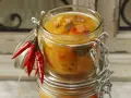 Ein Glas mit leckerem Aprikosen-Chutney-Rezept, garniert mit roten Chilis. Perfekt für herzhafte Gerichte.