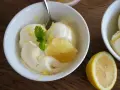 Erfrischendes zitroneneis selber machen: Cremiges Eis in einer Schüssel, garniert mit Zitronenspalte und Minze.