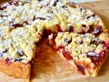 Saftiger pflaumenkuchen ohne hefe springform, mit Streuseln und Puderzucker bestäubt, auf einem Holzbrett.