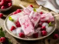 Erfrischendes Himbeer Joghurt Eis auf einem Teller mit frischen Himbeeren und Minze, serviert auf zerstoßenem Eis.