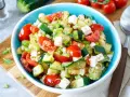 Erfrischender Zucchini Salat mit Tomaten, Feta und Frühlingszwiebeln, garniert mit frischen Kräutern. Ein leichter Genuss.
