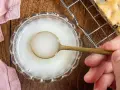 Ein Löffel mit zuckerguss ohne puderzucker in einer Schale. Daneben ein Stück Kuchen auf einem Gitter.