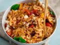 Ein köstlicher Nudelsalat mit Farfalle, frischen Tomaten, Mozzarella und sonnengetrockneten Tomaten, garniert mit Basilikum.