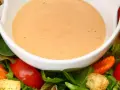 Cremiges French Dressing in einer weißen Schüssel, umgeben von frischem Salat, Tomaten und Karotten.
