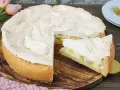 Ein saftiger Rhabarberkuchen mit luftigem Baiser, ein Stück davon ist bereits angeschnitten.