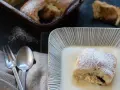Buchteln original rezept: Ein Buchtel in Vanillesauce, bestäubt mit Puderzucker. Im Hintergrund weitere Buchteln im Ofen.
