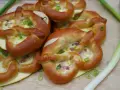 Herzhafte Brezeln gefüllt mit Käse und Speck, perfekt als partyrezepte aus dem ofen zum vorbereiten. Mit Frühlingszwiebeln garniert.