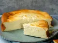 Saftiger Kuchen mit 250g Quark und Vanillepudding, goldbraun gebacken, auf einem Teller mit einem Stück daneben.