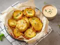 Korb mit knusprigen, gebackenen Zucchini im Teigmantel, bestreut mit Kräutern und Salz. Daneben eine Schale cremiger Dip.
