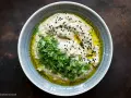 Cremiges Baba Ganoush, beträufelt mit Olivenöl, garniert mit frischer Petersilie und schwarzen Sesamkörnern.