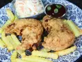 Knusprige chicken wings mit Pommes, Cole Slaw und BBQ-Sauce auf einem blau-weißen Teller.
