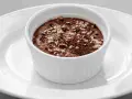 Ein cremiges Mousse au Chocolat, garniert mit Schokoladenraspeln und feinen Salzkristallen, serviert in einer weißen Schale auf einem Teller.
