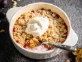 Ein köstlicher Zwetschgen Crumble mit Haferflocken, gekrönt mit einem Klecks Sahne, wartet darauf, genossen zu werden.