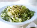 Ein leckerer Yum Yum Salat mit knackigem Eisbergsalat, Nudeln und Erdnüssen in einer weißen Schüssel.