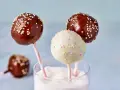 Drei bunte cake pops aus kuchenresten, mit Schokolade und Streuseln verziert, stecken in einem Glas voller Zucker.