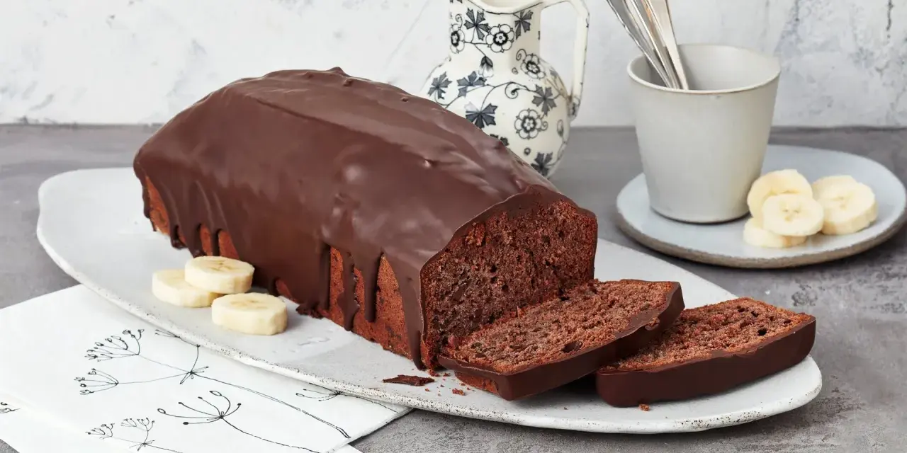Saftige Schoko-Bananen-Torte mit dunkler Schokoladenglasur, garniert mit Bananenscheiben. Ein Genuss für jeden Kaffeetisch.