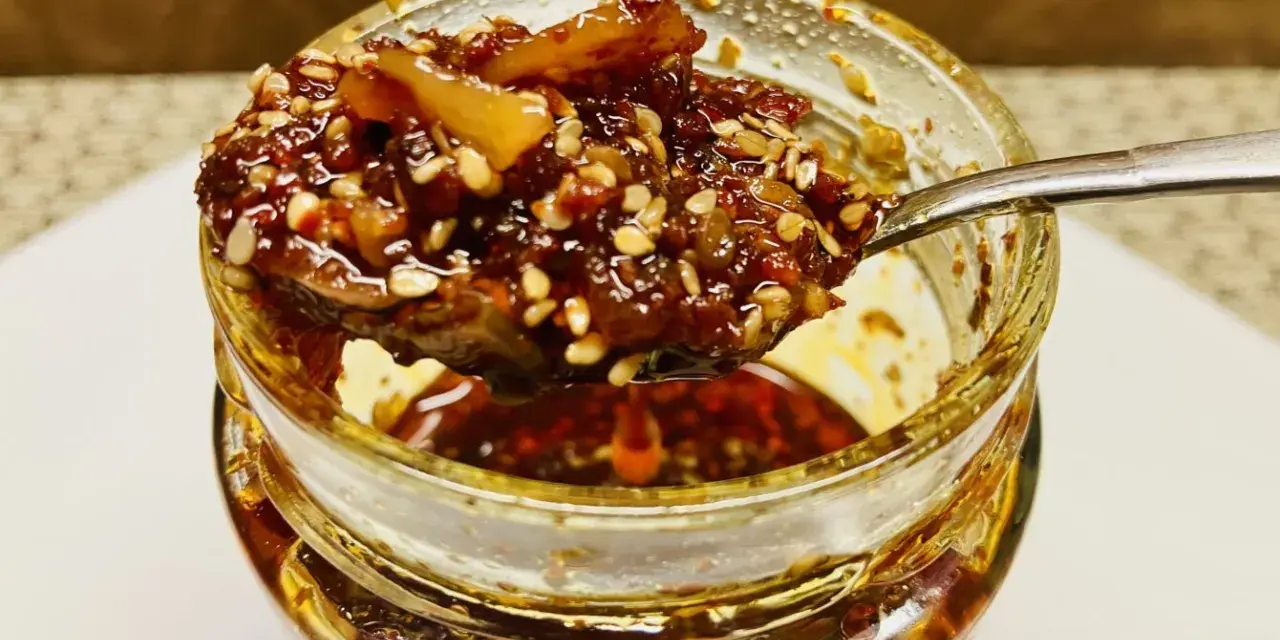 Ein Löffel voller knusprigem Chiliöl mit Sesam und Gewürzen, bereit, Gerichte zu verfeinern.