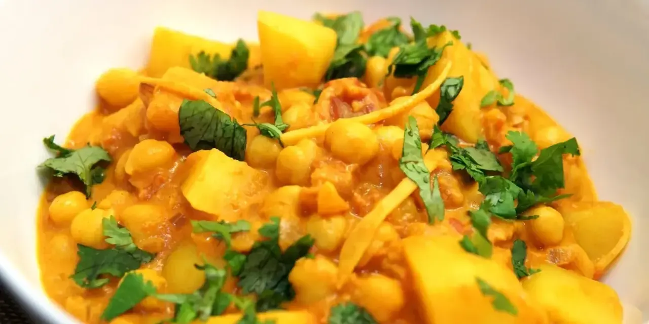 Herzhaftes Kichererbsen Curry mit Kartoffelstücken und frischem Koriander, ein Genuss für die Sinne.