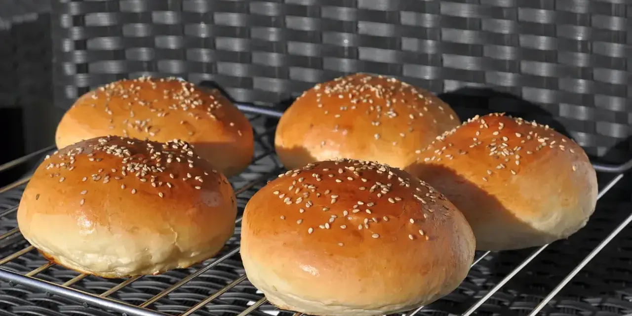 Fünf goldbraune Burgerbrötchen mit Sesam, frisch gebacken nach einem tollen burger buns rezept.