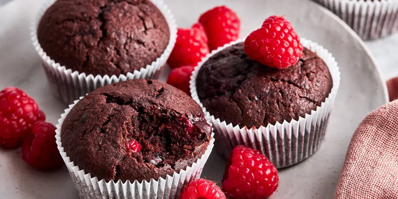 Saftige schoko himbeer muffins auf einem Teller, garniert mit frischen Himbeeren. Ein Genuss für alle Sinne!