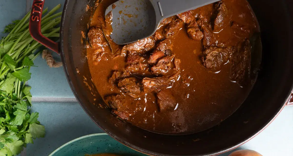 Herzhaftes Gulasch im Gusseisentopf, das beste Gulasch Rezept original Oma. Mit Petersilie und Zwiebeln.