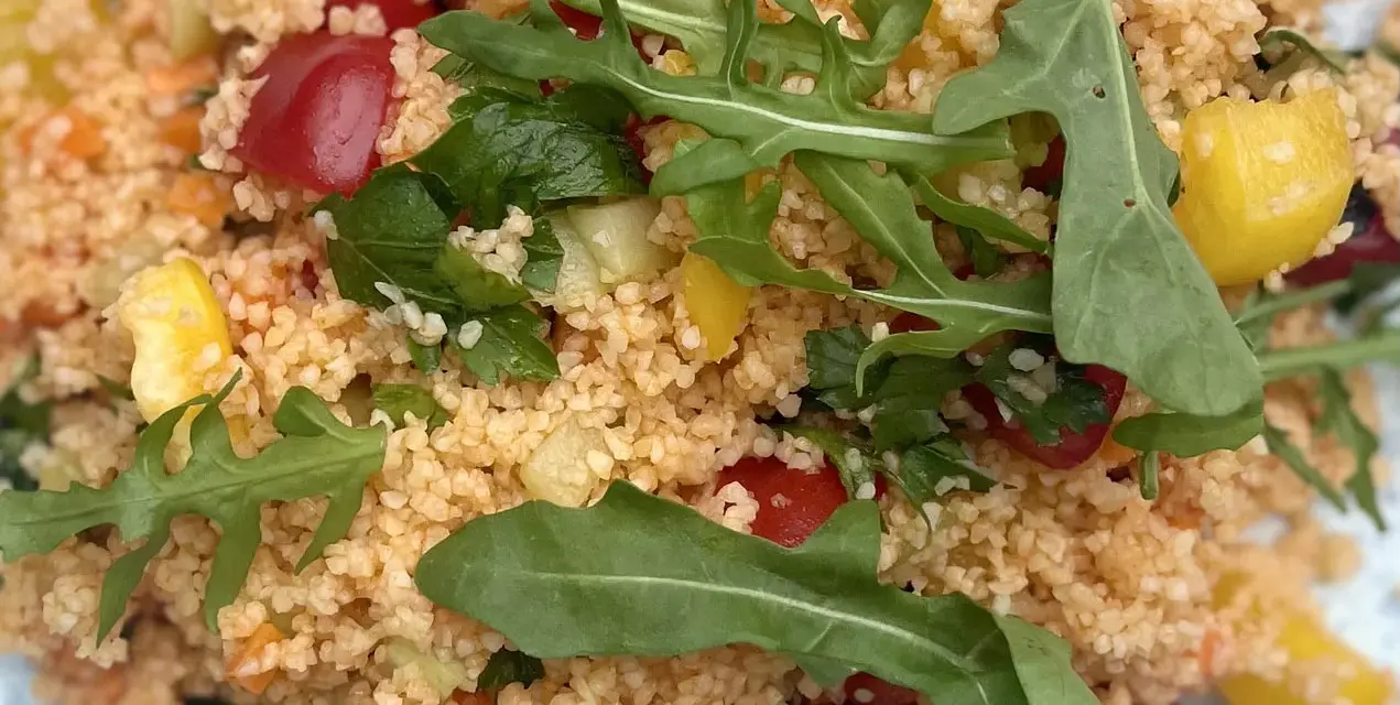 Frischer Couscous-Salat mit Tomaten, Gurken, Paprika und Rucola. Ein leichter und gesunder Genuss.