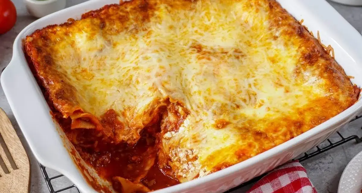 Herzhafte Lasagne mit Schmand und goldbraun überbackenem Käse in einer weißen Auflaufform.