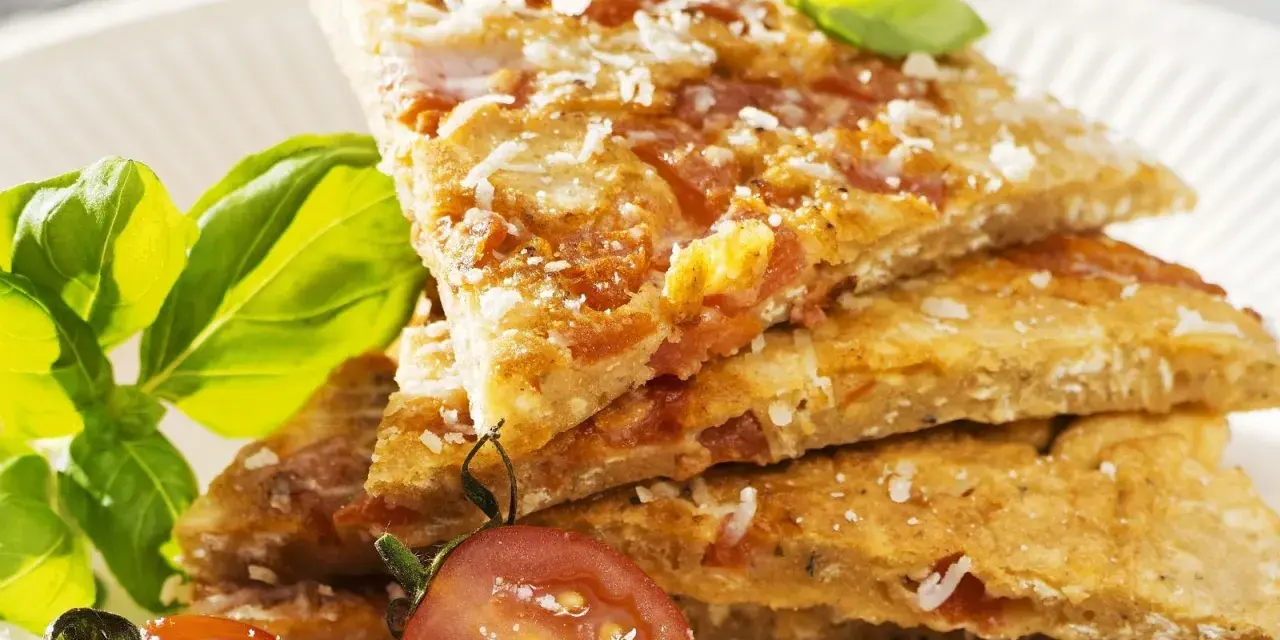 Herzhafte Hauptspeise: knusprige Eierkuchen-Schnitten mit Tomaten und Parmesan, garniert mit Basilikum und Kirschtomaten.