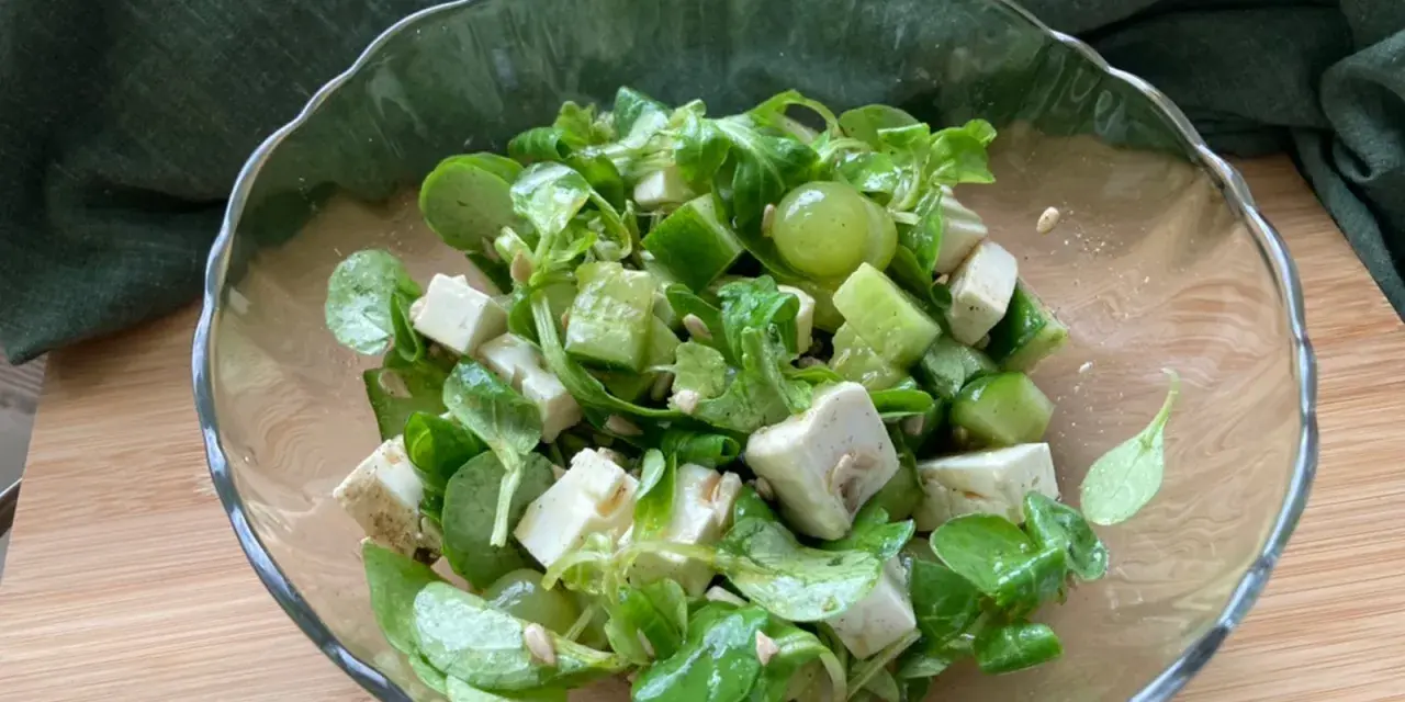 Erfrischender weintrauben feta salat mit Gurkenwürfeln und Sonnenblumenkernen in einer Glasschüssel.