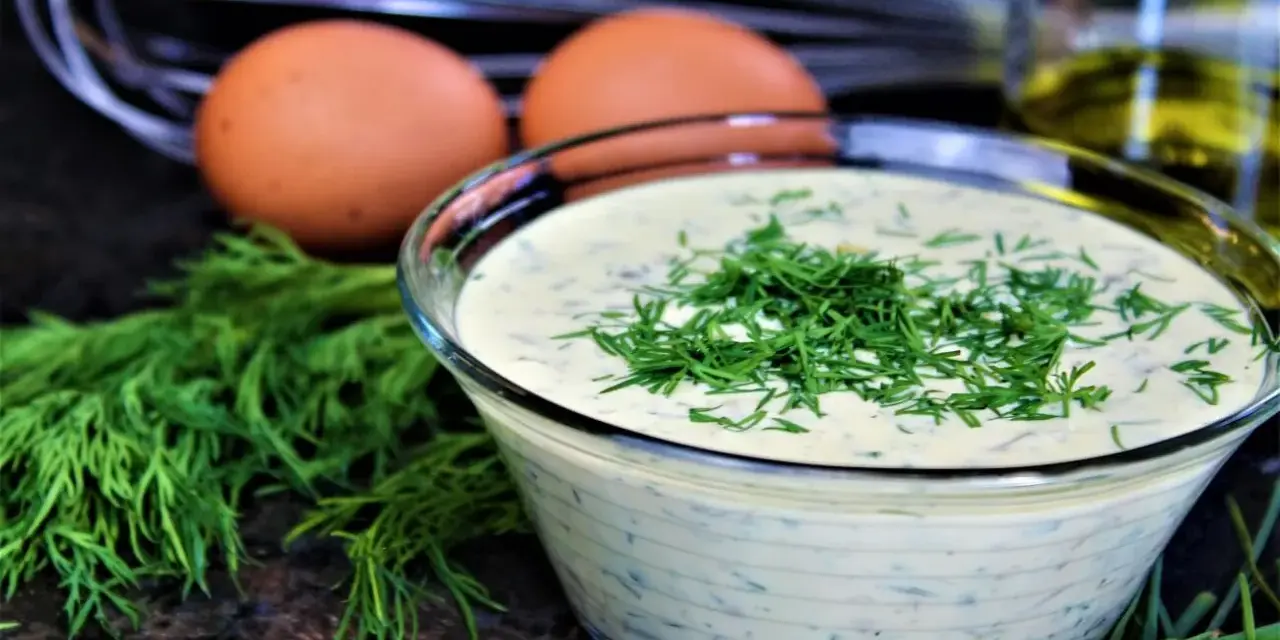 Schüssel mit cremiger Remoulade, garniert mit Dill. Eier und Kräuter deuten auf ein authentisches Remoulade Rezept Original hin.