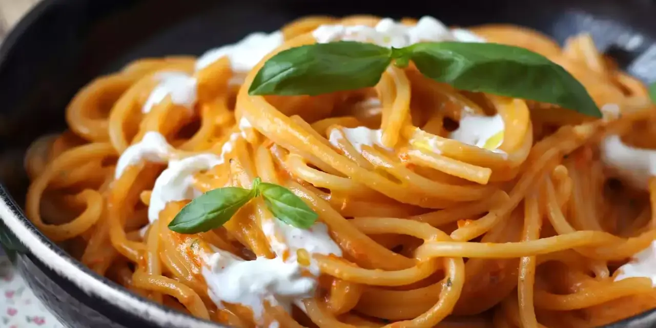 Spaghetti mit cremiger Tomatensoße und frischer Burrata, garniert mit Basilikum. Ein Genuss für alle Liebhaber von Pasta.