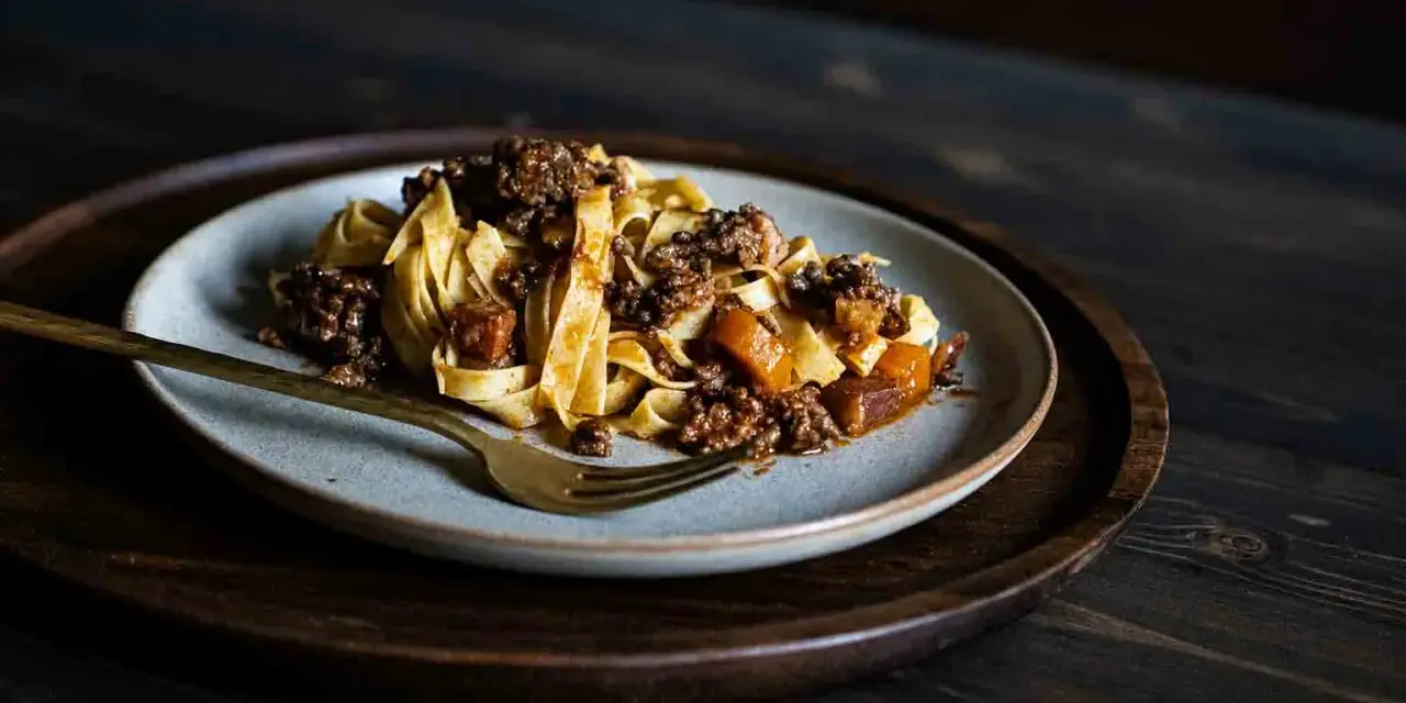 Teller mit breiten Bandnudeln und herzhafter Hackfleischsauce, eine köstliche spaghetti bolognese.