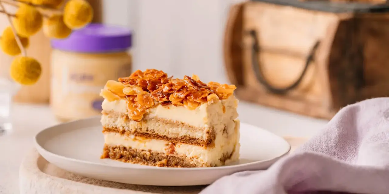 Ein Stück Bienenstich Tiramisu mit karamellisierten Mandeln und cremiger Füllung auf einem Teller.