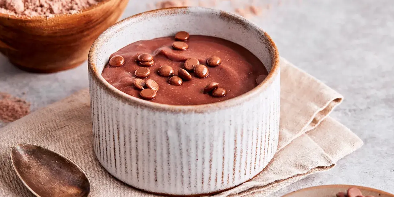 Schokoladenpudding, frisch zubereitet, mit Schokostückchen garniert. Perfekt, um Pudding selber machen zu lernen.