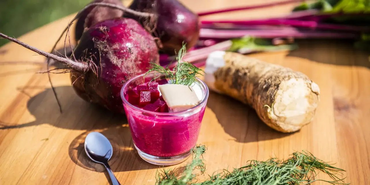 Rote Bete Mus Rezept: Frische rote Bete, Meerrettich und Dill auf Holztisch. Ein Glas mit leuchtend pinkem Mus, garniert mit Würfeln und Dill.
